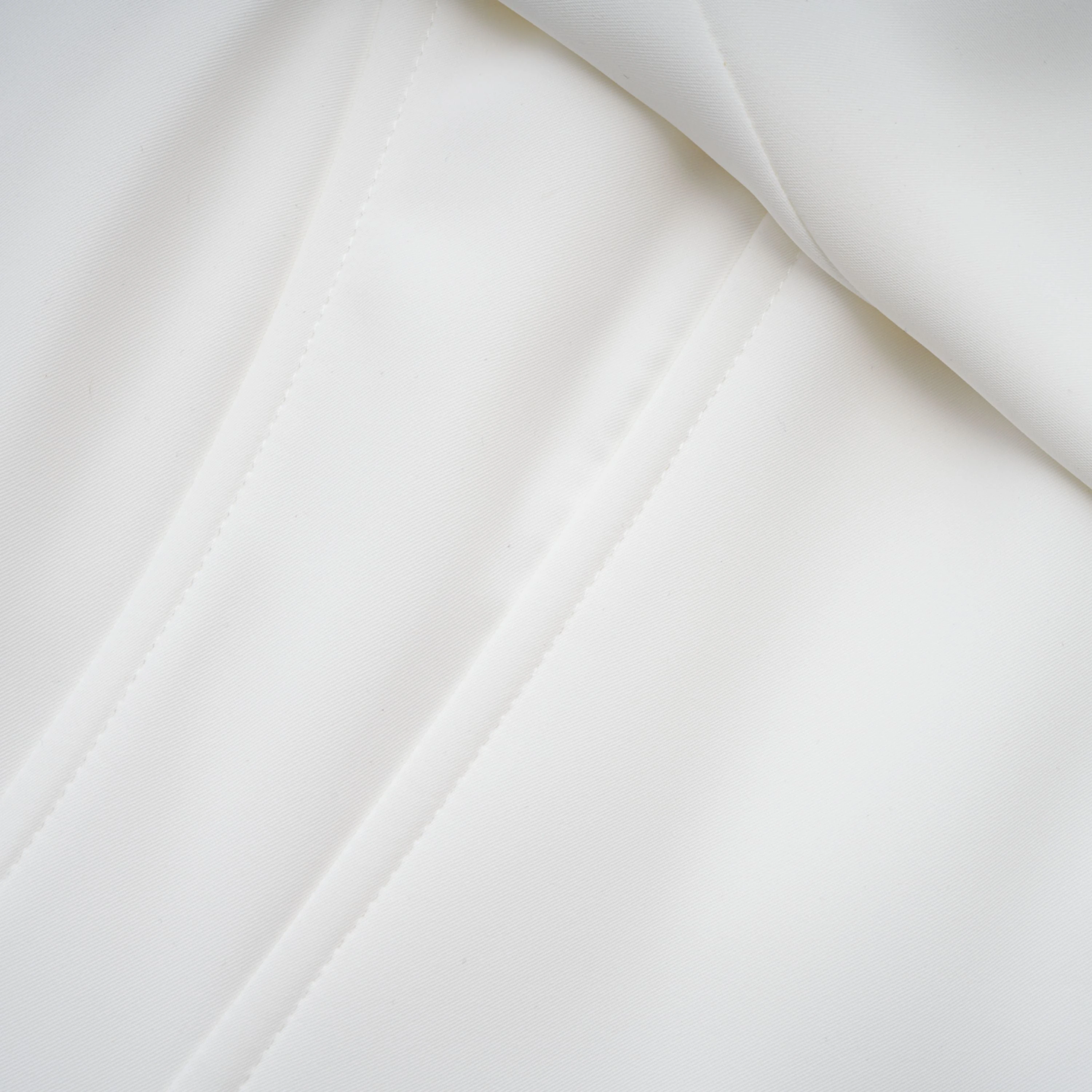 White off-the-shoulder gown with a draped bodice and cascading side ruffles